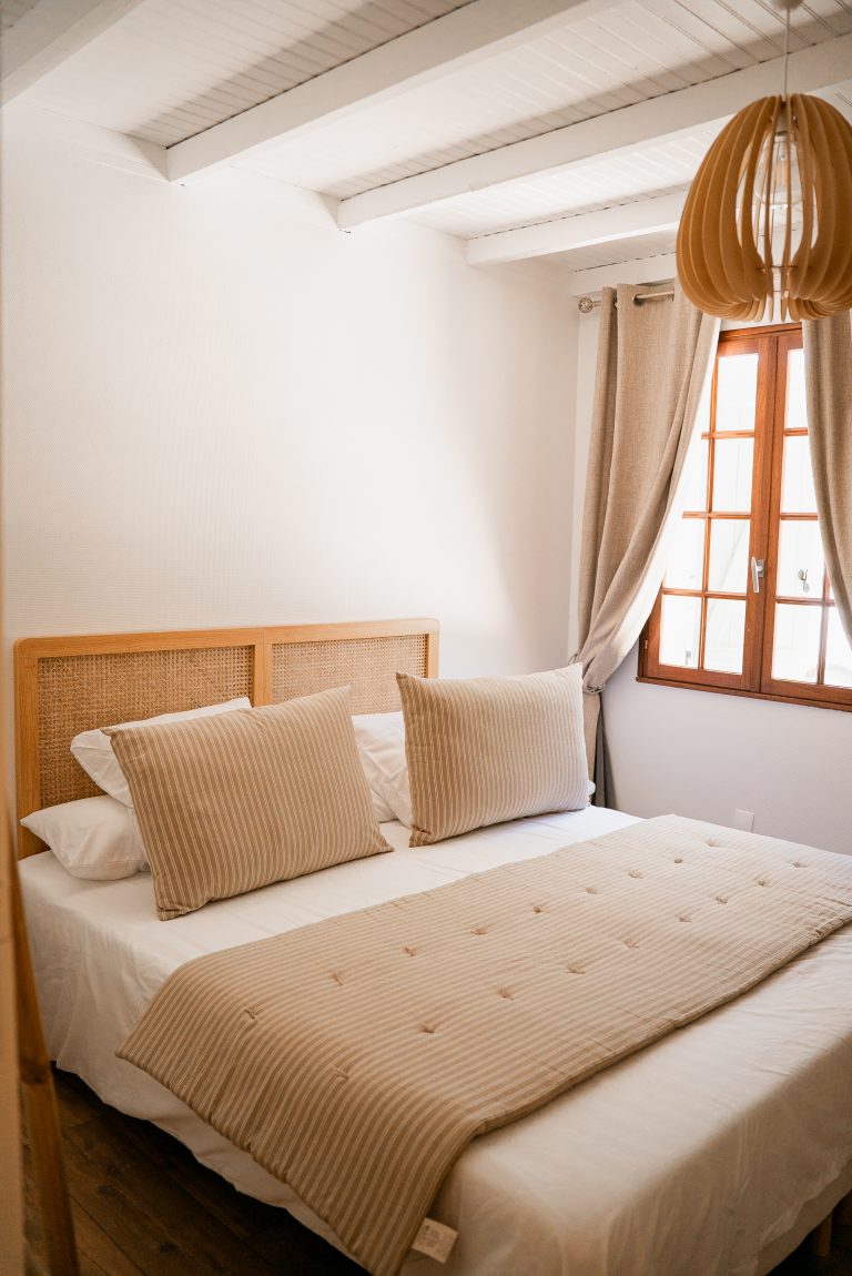 Lit double dans la chambre 1 avec une décoration aux tons beige, blanc et marron