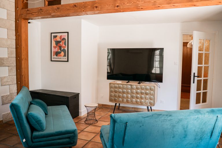 Salon avec télé écran plat et deux canapés-lits dans la villa Ô Sud Location