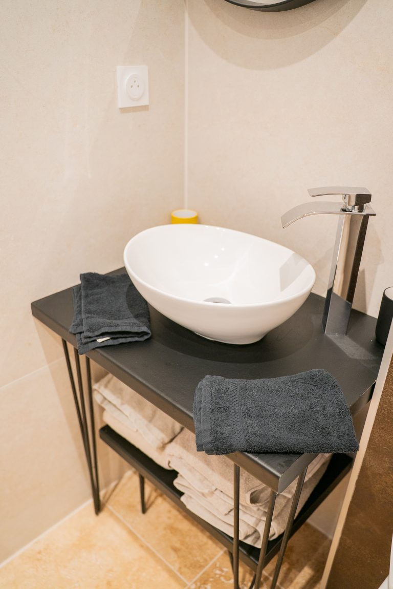 Vasque moderne posée sur un meuble en bois dans la salle de bain de la villa Ô Sud Location