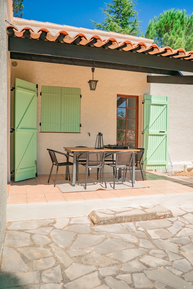 Terrasse couverte avec table et chaises d’extérieur à la villa Ô Sud Location