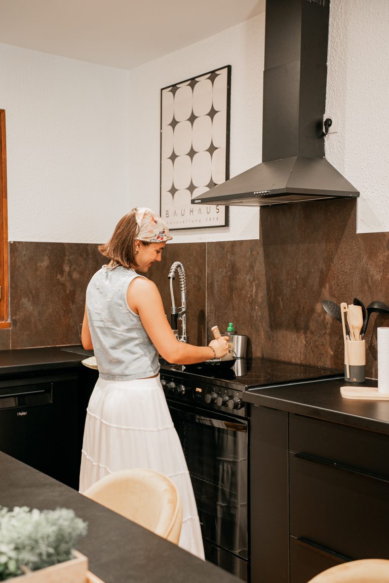 Femme souriante dans la cuisine lumineuse et moderne de la villa Oléa, Ô Sud Location
